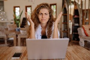 A stressed woman in front of her laptop. Tap into the power of StoryBrand marketing to define and solve a customer’s problem.