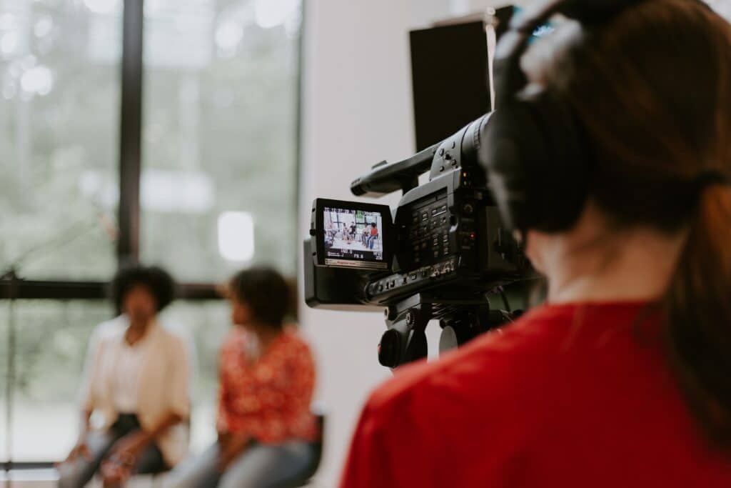 Videographer filming a meeting. Product and service videos can be used to maximize sales and showcase a brand's personality.